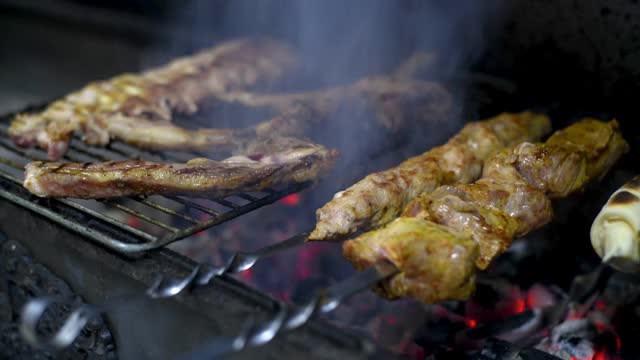 肉在炭火上烤。烧烤肋骨。将牛肉、羊肉、猪肉、鸡肉等多汁的肉类放在明火上，自然熏制。视频素材