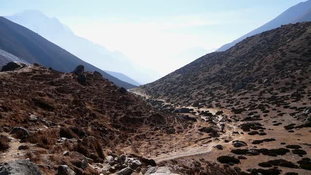 在明媚的午后阳光下，徒步者和搬运工们爬上通往喜马拉雅山上珠穆朗玛峰大本营徒步旅行的路线，前往尼泊尔昆布的Dinboche。视频素材