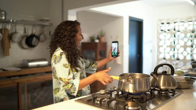 中年女性在家做饭的时候用智能手机打视频电话视频素材