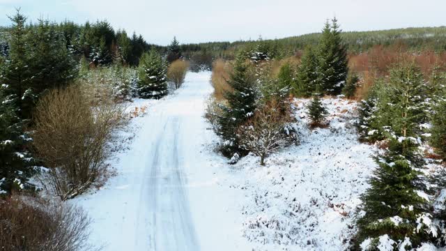 这是苏格兰西南部邓弗里斯和加洛韦被雪覆盖的乡村公路的高角度无人机拍摄的画面视频素材