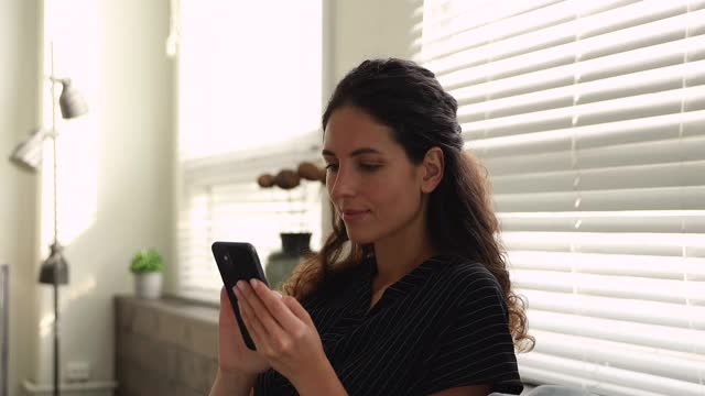 女人在智能手机上阅读收到了好消息庆祝成功视频素材