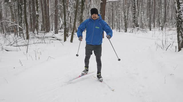 一个年轻人正在冬季森林里进行越野滑雪。运动员滑冰。视频素材