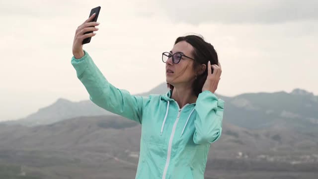 一个女人在山里用智能手机自拍。视频素材