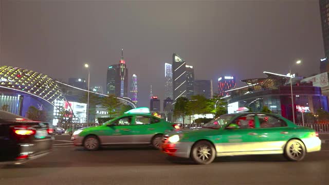 汽车在镜头前分散开来，背景是广州的摩天大楼。大城市的夜生活视频素材