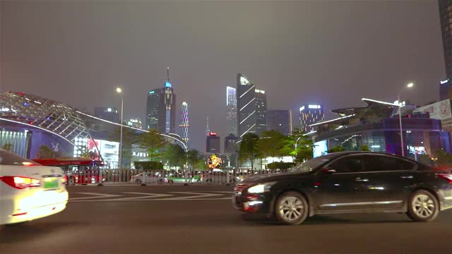 汽车在镜头前分散开来，背景是广州的摩天大楼。大城市的夜生活视频素材