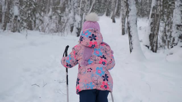 小女孩在冬天的森林里学习滑雪视频素材