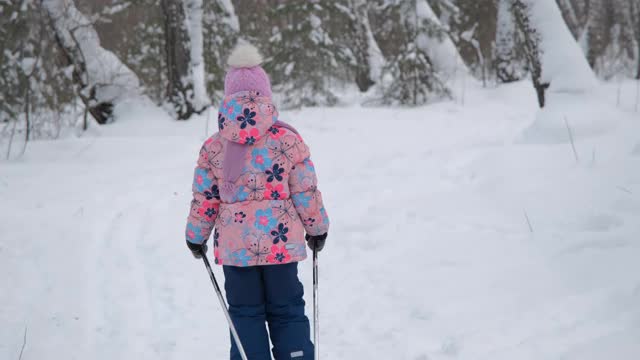 小女孩越野滑雪在一个公园视频素材