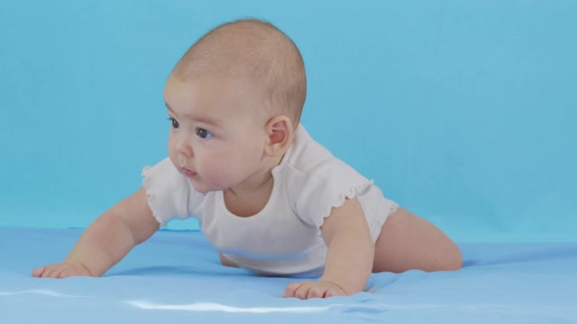 蹒跚学步的女婴趴在肚子上微笑着。视频素材