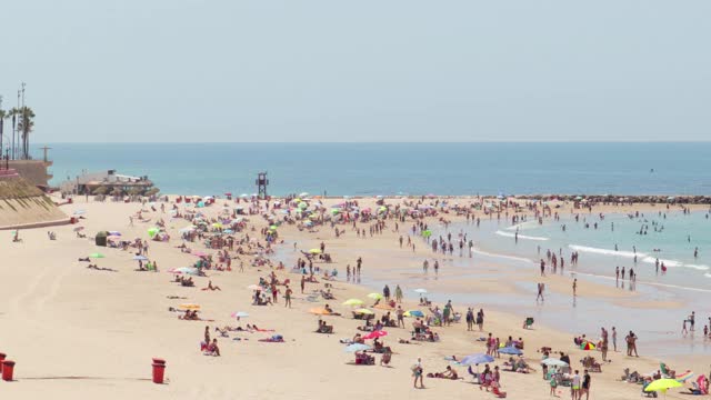 著名的海滩“Playa de Santa María del Mar”。人们在海滩上享受炎热的一天视频素材