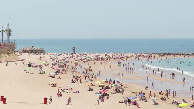 著名的海滩“Playa de Santa María del Mar”。人们在海滩上享受炎热的一天视频素材