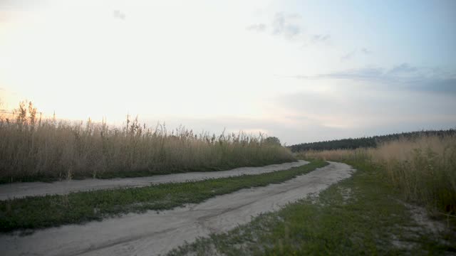 日落时分，骑自行车的人在田野里的土路上骑行。视频素材