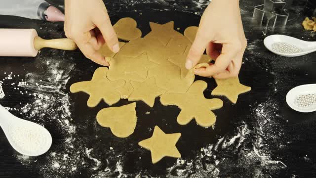 女性的手会为圣诞节或情人节制作各种形状的姜饼。女人在黑木桌上做饼干视频素材