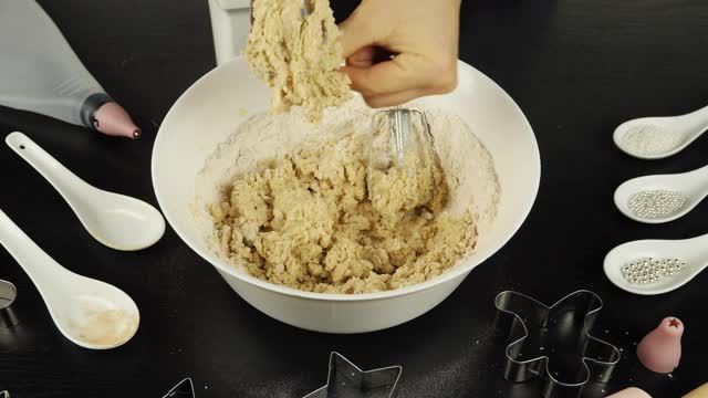 女人的手正在从搅拌器刀片上取面团。制作美味的香料面团，用于制作饼干、糕点或饼干。情人节或圣诞节的饼干视频素材