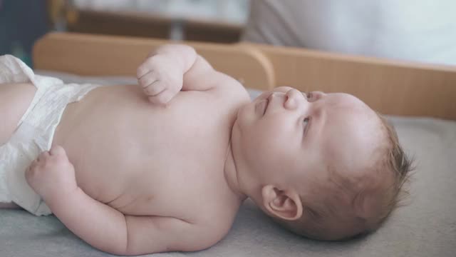 儿科医生翻转不安的婴儿男孩在白色尿布视频素材