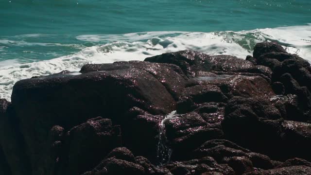 跟着白色泡沫的海浪拍打海滩上的岩石全高清视频素材