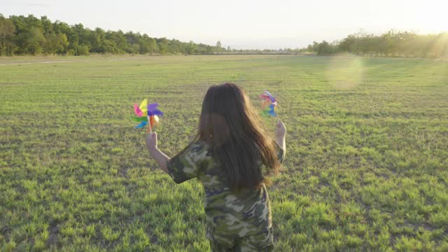 快乐的女孩带着玩具飞机在公园的绿地上奔跑视频素材