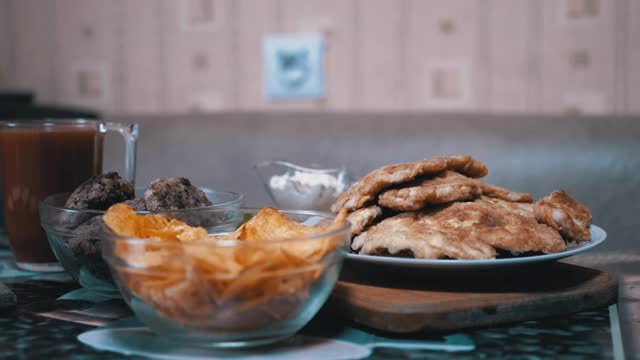 饥饿的男孩从桌子下的手在没有人看到的时候从盘子里拿走了薯片视频素材