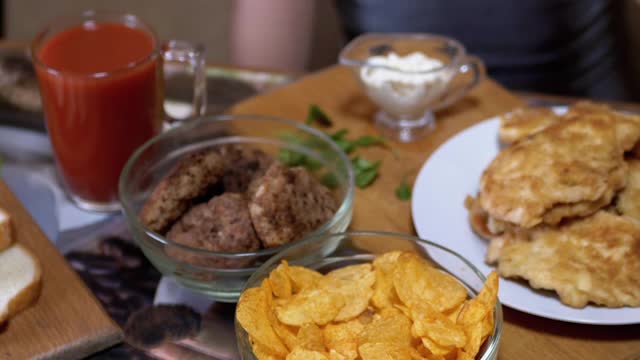 饥饿的小手从盘子里拿起脆脆的金色薯片。晚餐中的垃圾食品视频素材