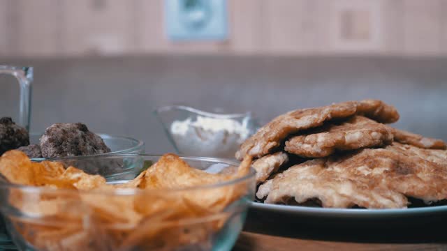 饥饿的男孩从桌子下的手在没有人看到的时候从盘子里拿走了薯片视频素材