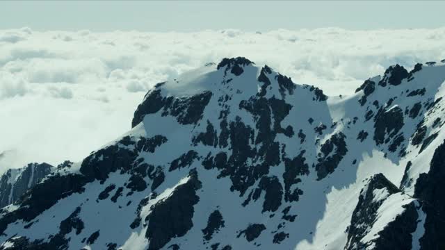 空中跟踪拍摄的一个近的山脉山峰通过高海拔白云视频素材