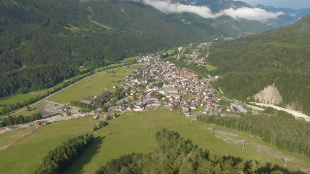 空中风景:田园小镇Kranjska Gora被郁郁葱葱的山景所包围。视频素材