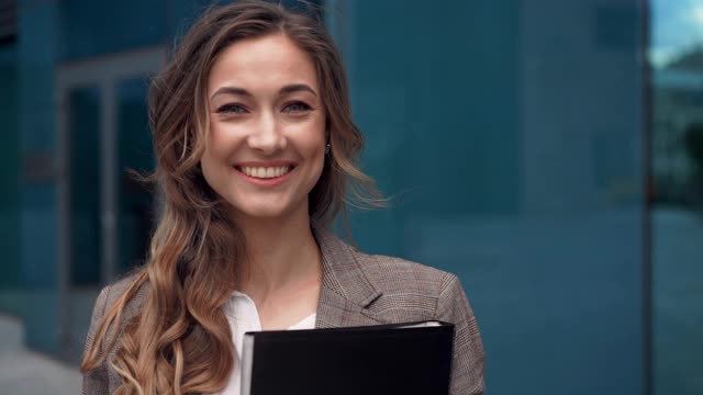 女商人成功的女商人站在户外公司大楼的外部。兴奋的白人自信职业女性中年视频素材