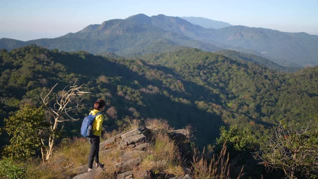 女性旅行者徒步登山，用智能手机拍照视频素材