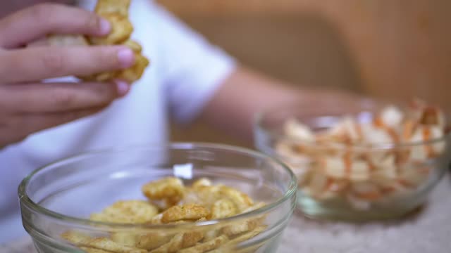 小孩的手从盘子里拿薯条，饼干。吃有害的零食视频素材