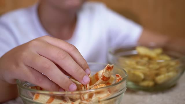 小孩的手从盘子里拿薯条，饼干。吃有害的零食视频素材