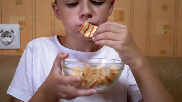 饥饿的少年把盘子里的薯条放进嘴里。吃快餐视频素材