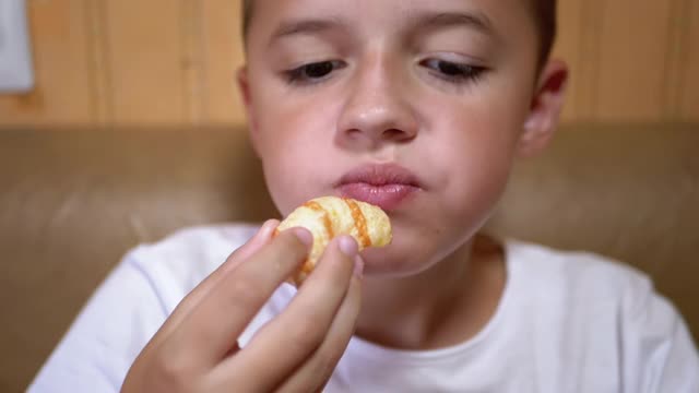 饥饿的白人孩子用手把薯片放进嘴里。男孩吃快餐视频素材