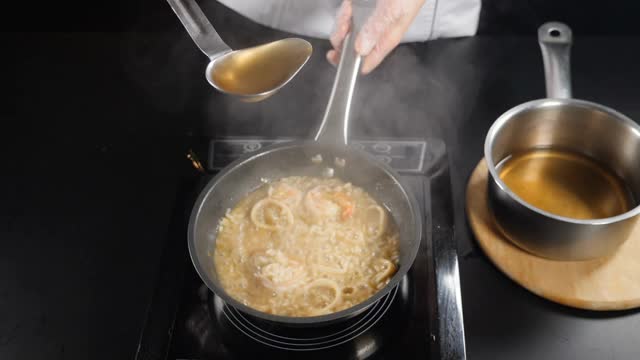 意大利海鲜餐馆。前视图。厨师将鱼汤从大勺倒入调味饭中。缓慢的运动。传统的意大利美食。全高清视频素材