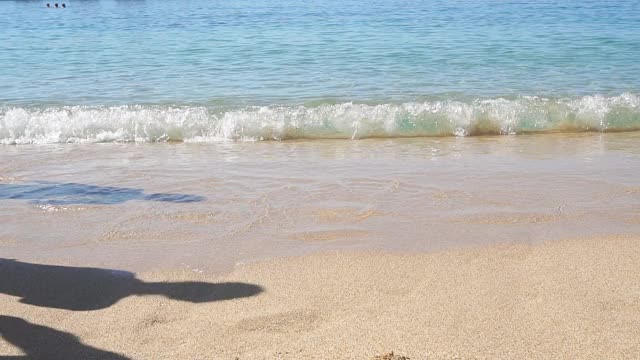 脚在沙滩上赤脚行走的特写海浪。男人和女人的脚走在海滩在一个阳光灿烂的日子视频素材