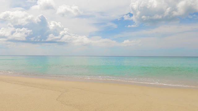 美丽的深蓝色海水表面，平静的海浪冲击着金色的沙滩视频素材