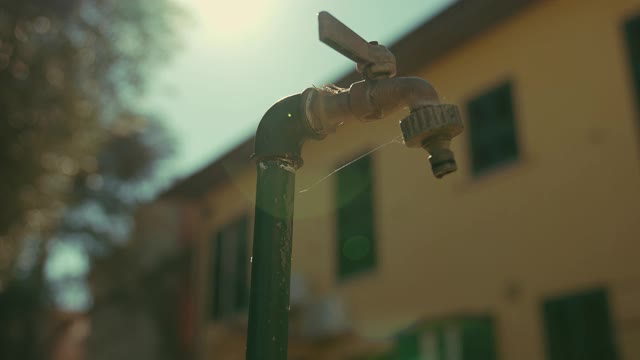 电影移动拍摄的一个室外水龙头缓慢滴水。泄漏的自来水。帮助节约用水。慢动作拍摄视频素材