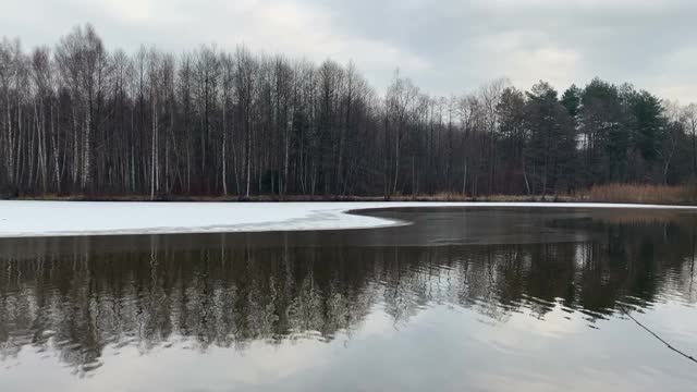 池塘上的冬季景观。湖上的冰。池水中树木的倒影。视频素材