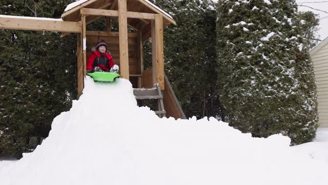 小男孩在冬天的户外雪地上滑行视频素材