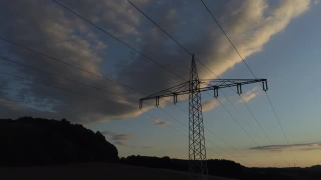 架空下和周围的架空电线杆与山和塔对着傍晚的天空和夕阳视频素材