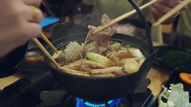 一家人在日本餐馆吃涮涮锅晚餐。和家人一起吃涮锅饭。视频素材