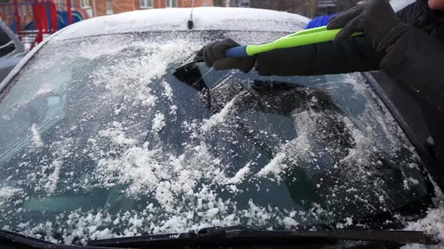 冬天,寒冷。司机用一种特殊的刮刀把挡风玻璃上的冰雪刮干净视频下载