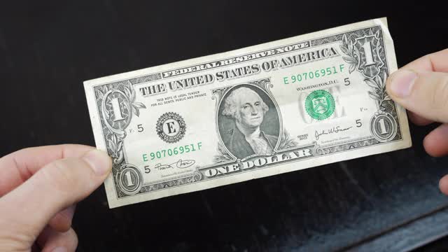 男性手中正握着1美元的钞票，近距离看。贫困和金融危机的概念。收入下降。企业经济的概念视频素材