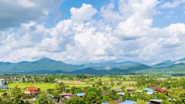美丽的稻田农场和村庄小镇在Pua区在收获季节与Doi Phu Kha山的背景，南省，泰国-时间流逝视频素材