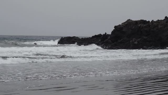 在寒冷多云的天气里，暴风雨和汹涌的海浪会撞击海岸。急流和白色泡沫冲击着海洋的沙滩。失望和悲伤。视频素材