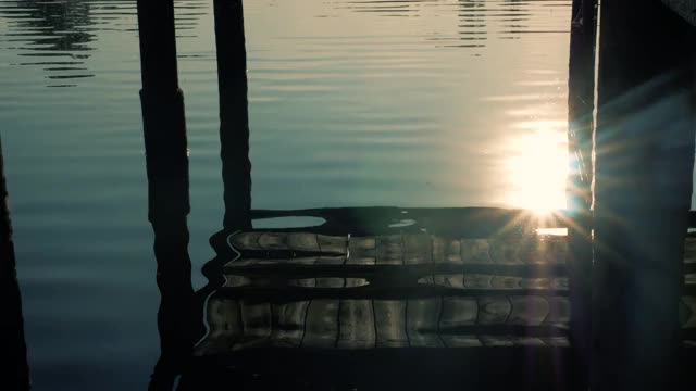 夕阳在河岸上，美丽的木桥倒映在水面上，连绵不绝的江水和木桥。视频素材