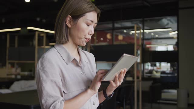 亚洲女商人在现代办公室里使用数字平板电脑视频素材