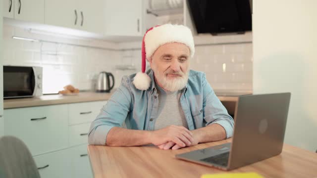 Happy grandpa in New Year hat by laptop app在线与家人聊天视频素材