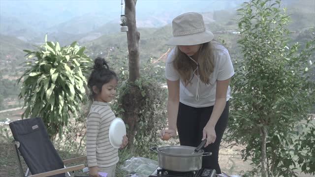 母亲和女儿花周末时间一起露营和做早餐视频素材