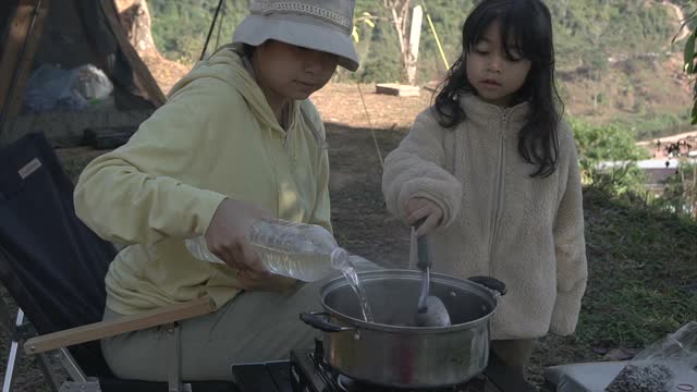 母亲和女儿花周末时间一起露营和做早餐视频素材