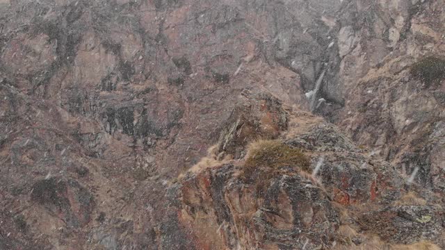 飞过高山上的岩石在下雪时鸟瞰瀑布视频素材