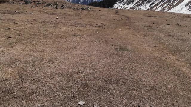 低空飞过一个山谷，有一条小路，石头落在山上。鸟瞰图视频素材